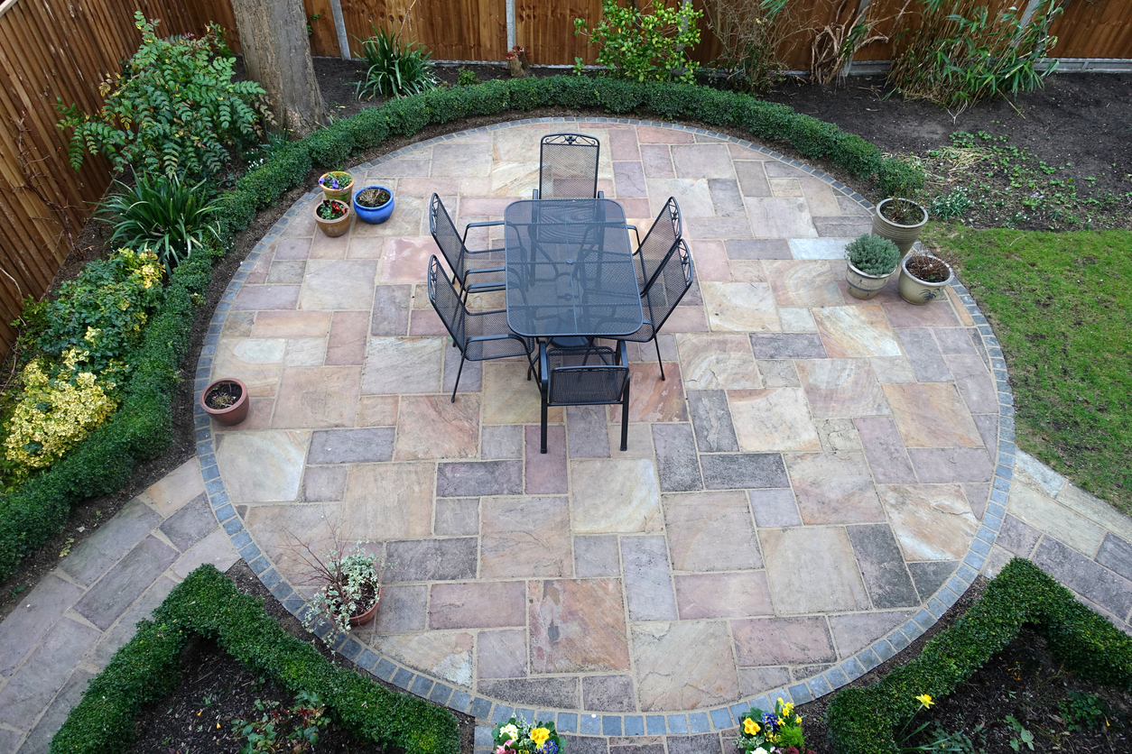 Circular paver patio with artificial turf in backyard