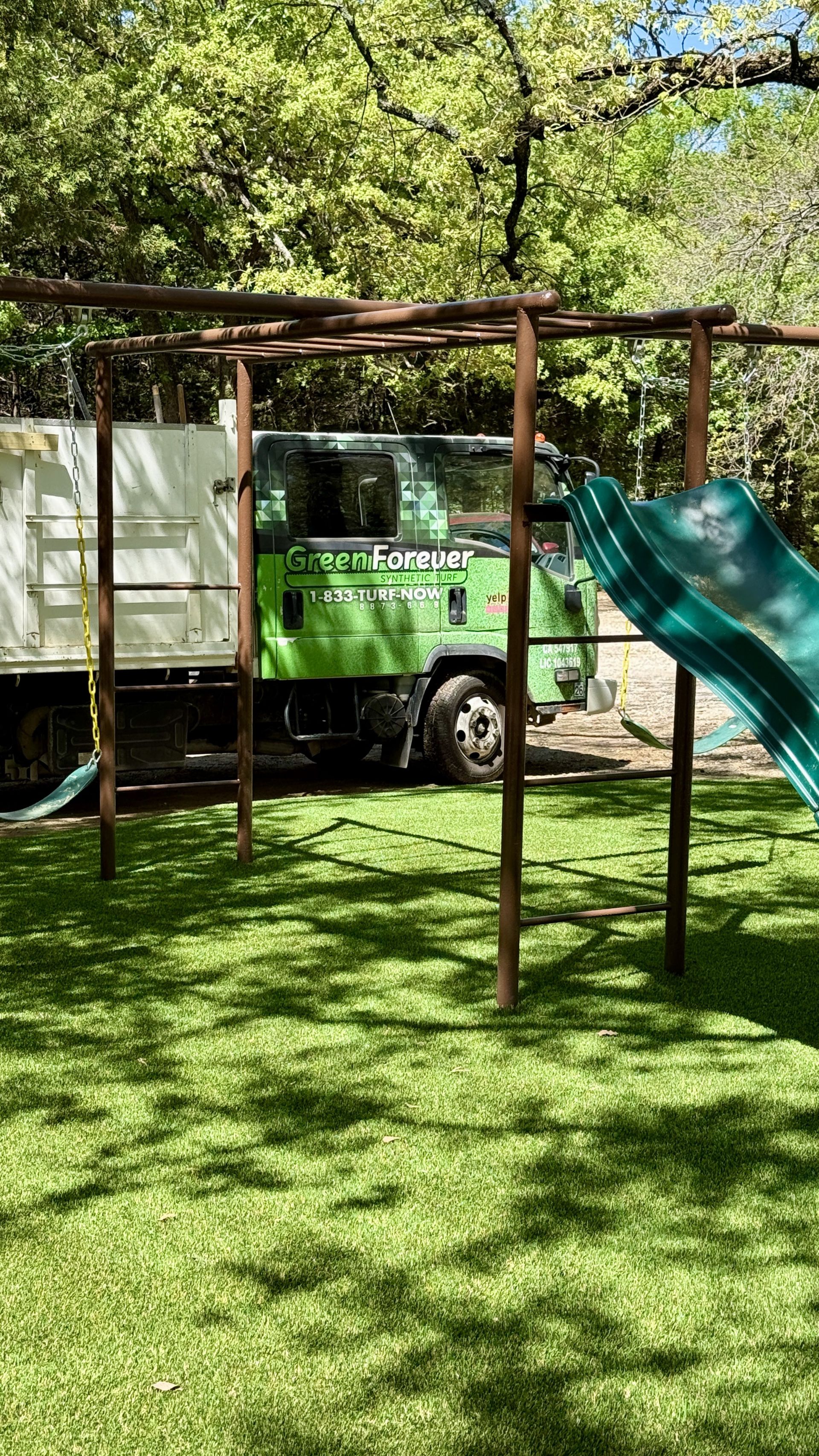 Green Forever Turf service truck at a finished playground turf installation in DFW