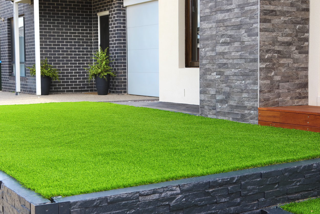 Modern front yard with artificial turf and stone wall in DFW