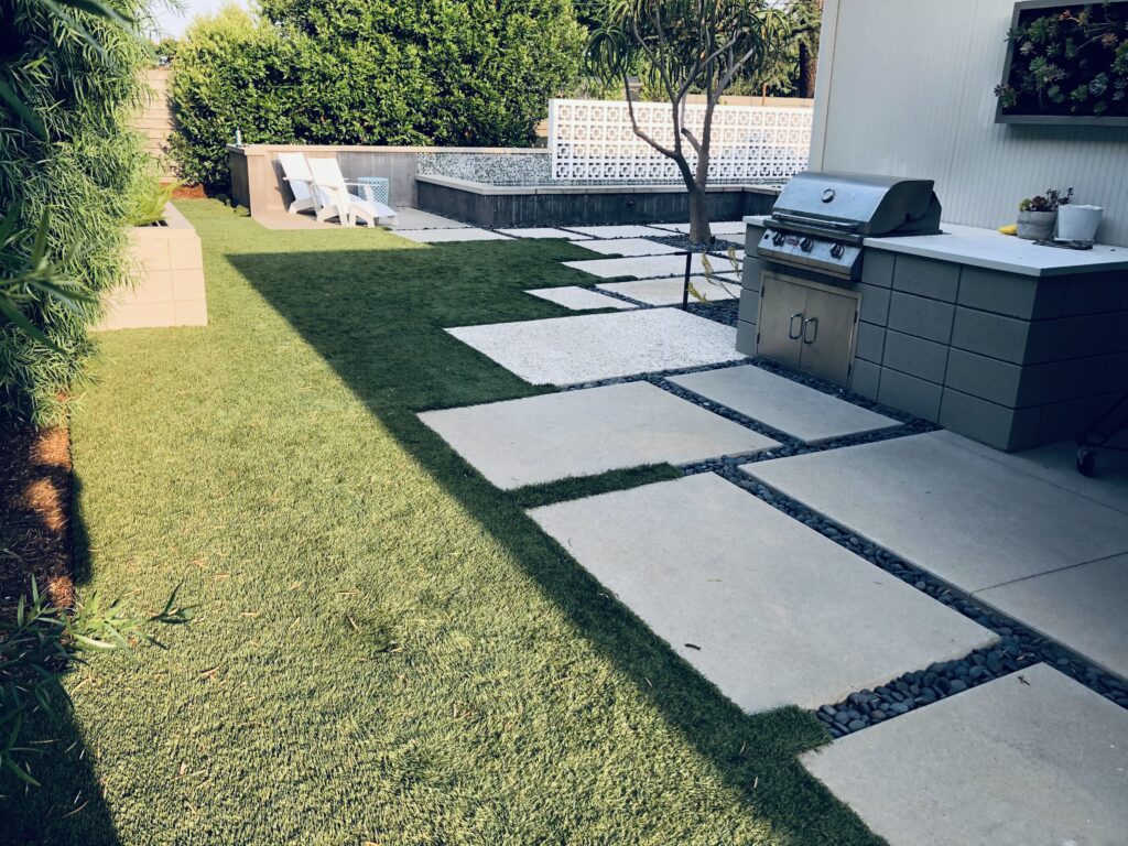Paver walkway with artificial turf inlays in a backyard