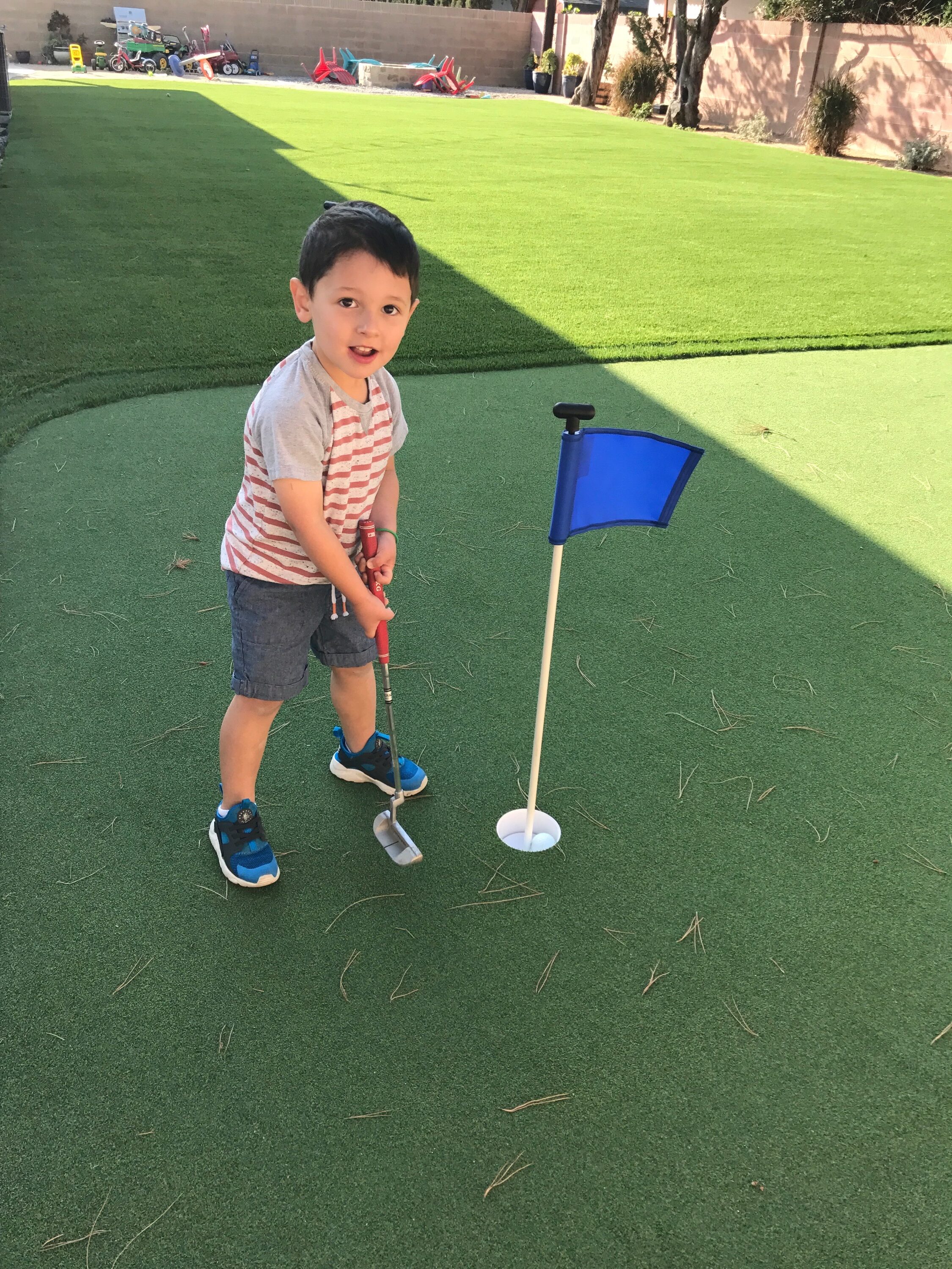 Putting green with child practicing chipping - Green Forever Turf Texas