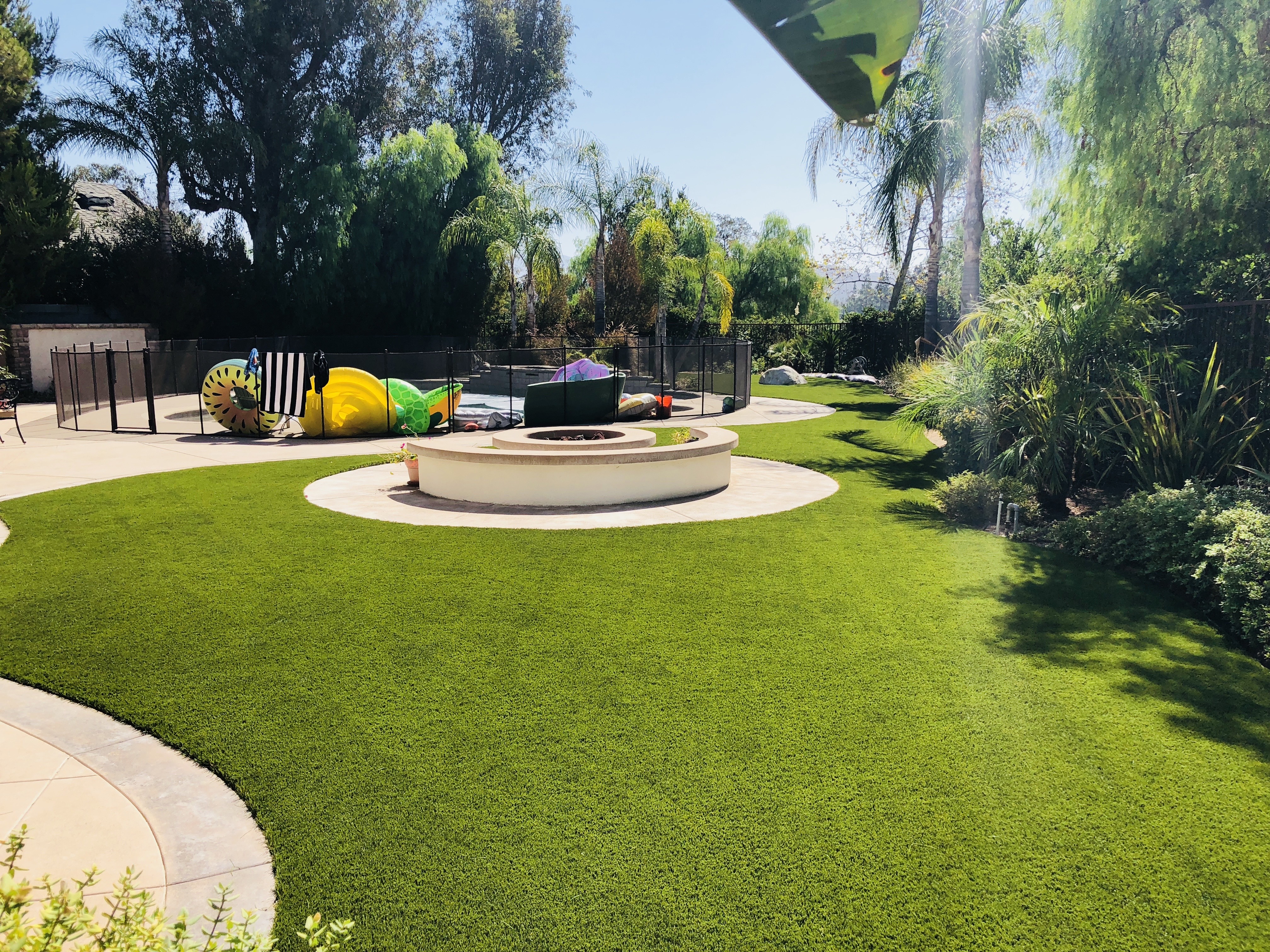 Custom artificial turf backyard installation with firepit and playset by Green Forever Turf Texas
