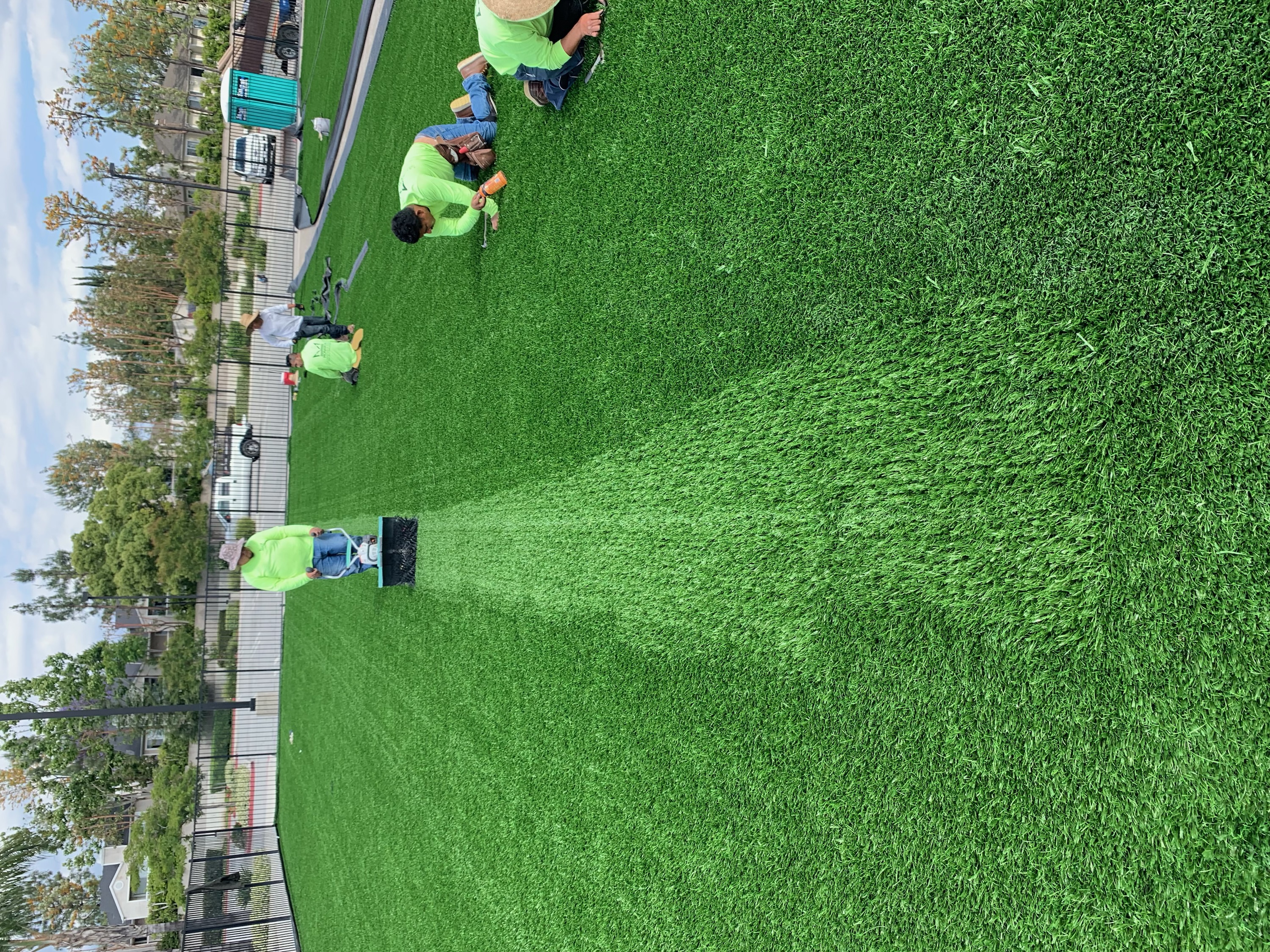 Sports field installation crew brushing turf - Green Forever Turf Texas